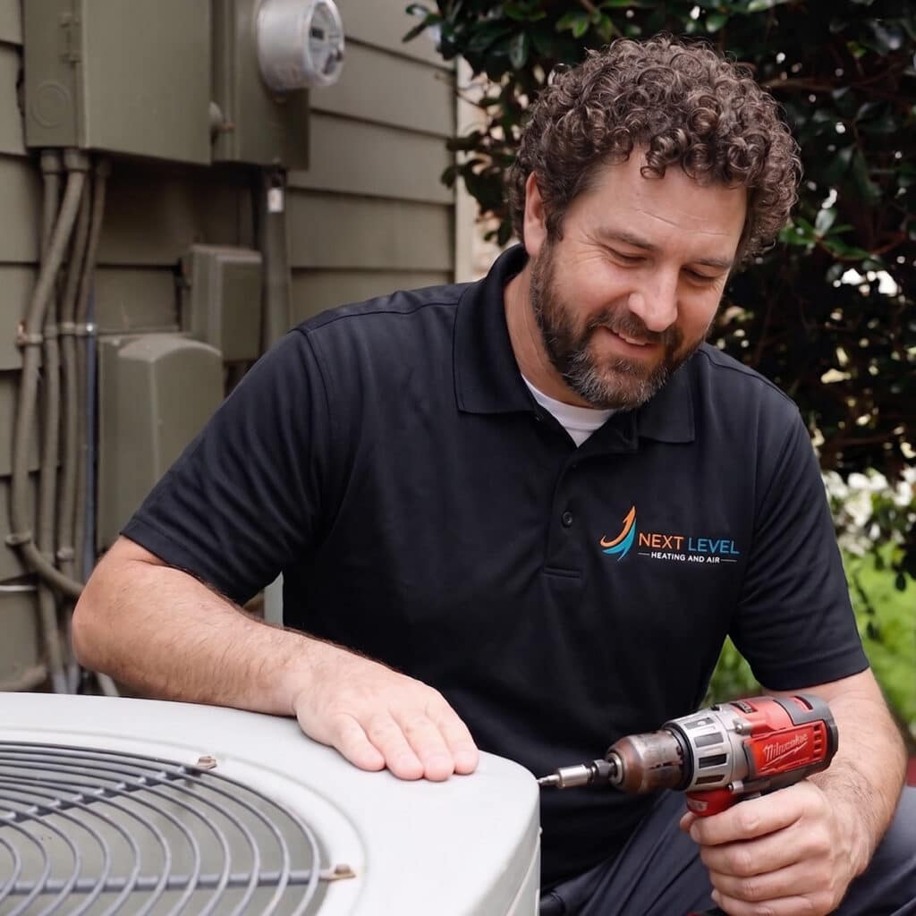 Next Level Heating and Air technician using drill on condenser unit panel