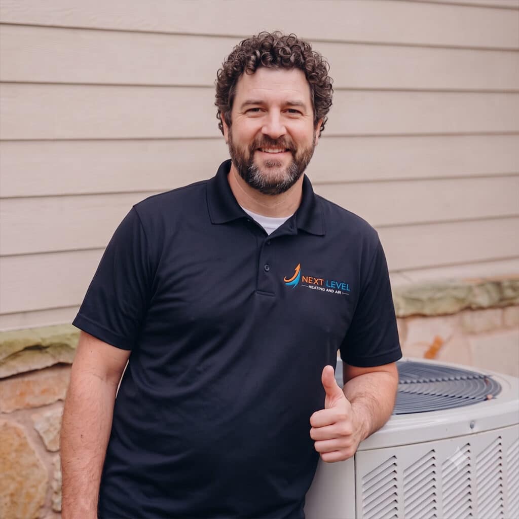 Next Level Heating and Air technician giving thumbs up beside condenser unit