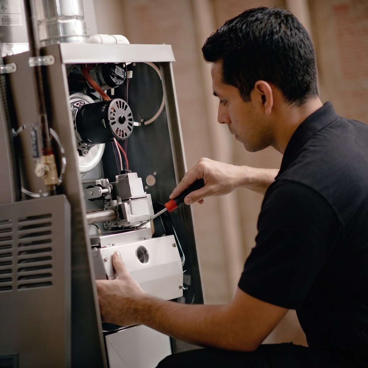 HVAC technician using screwdriver to repair gas furnace burner assembly